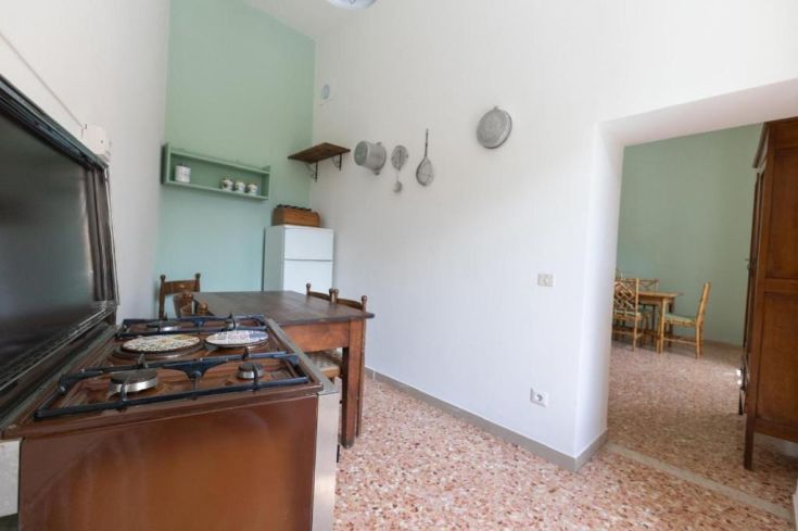 Spacious kitchen with cooking surface, refrigerator, and a table suitable for family gatherings.