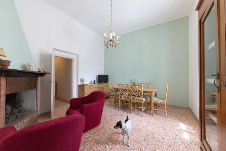 A bright living room with red sofas and a dining table, adorned with a classic chandelier.