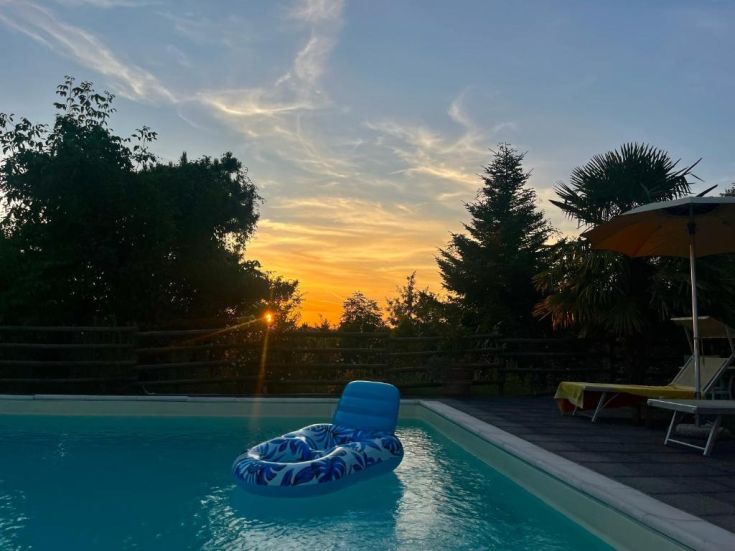 A tranquil pool at sunset, featuring a floating mattress and a serene atmosphere.