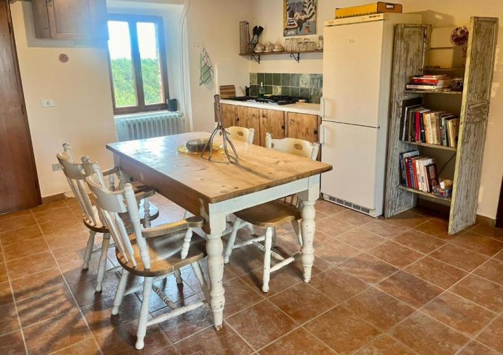 Cozy kitchen with a wooden table and white chairs, perfect for shared meals.