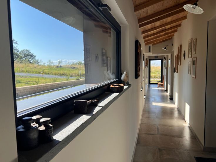 Un corridoio ben illuminato con affaccio sulla campagna umbra, arredato con elementi semplici in stile rustico.