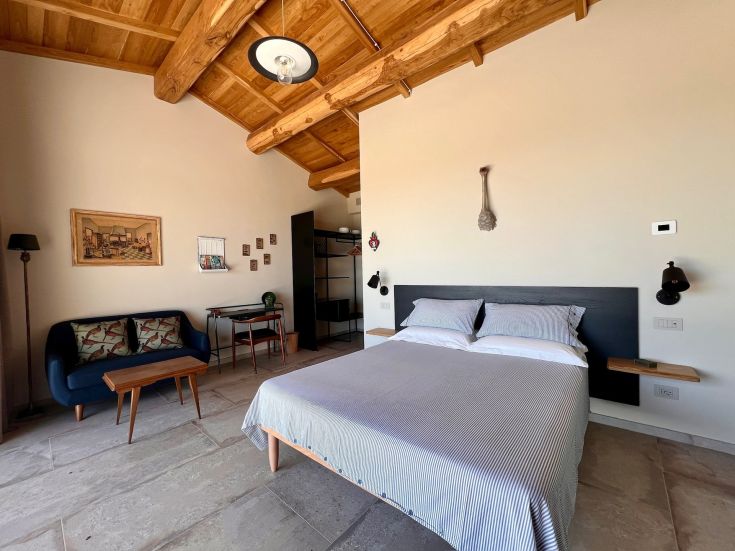 Interno di una camera rustica con arredamento semplice e tetto in legno, perfetto per un soggiorno tranquillo in Umbria.