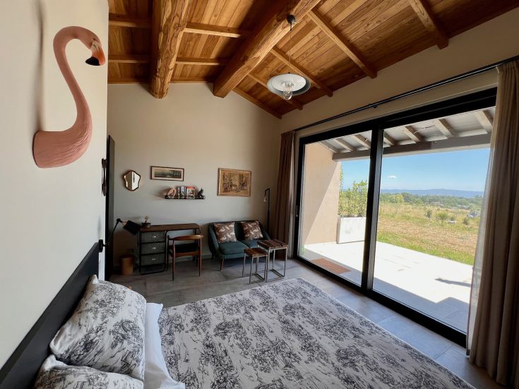 Camera semplice con un'atmosfera accogliente, arredamento moderno e un'apertura su un'area esterna luminosa.