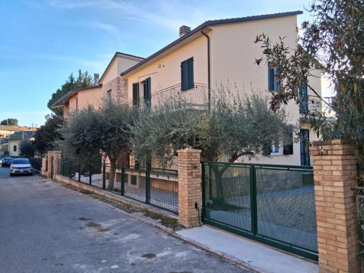 A house with a spacious garden adorned with olive trees, located in a peaceful and welcoming environment.