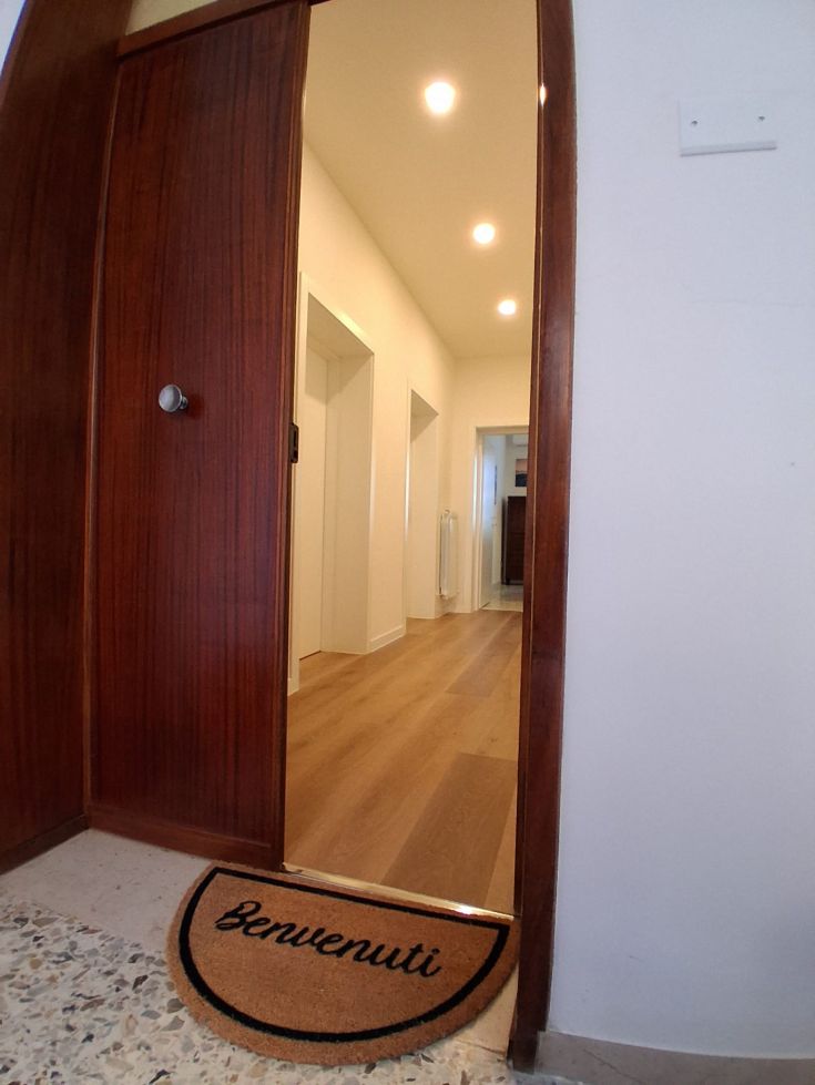 The entrance of a house with a welcome mat, simply furnished.