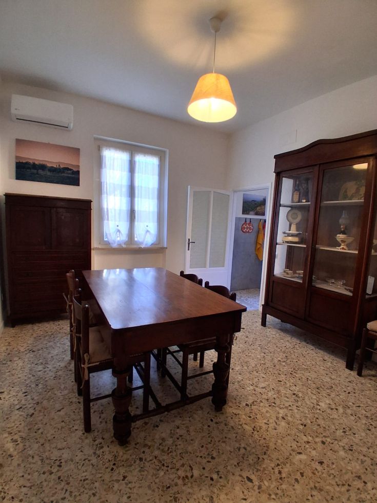 A simple dining room with a wooden table and good natural lighting.