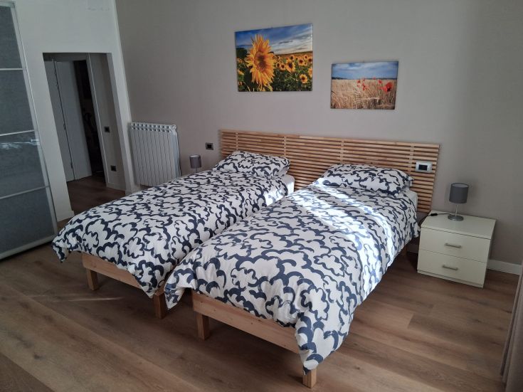 A double room featuring two single beds, simply furnished with windows allowing natural light.