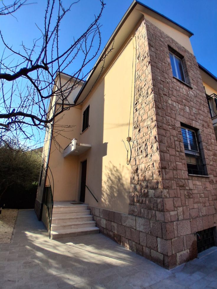 Contemporary house with stone elements, surrounded by a well-kept garden under a serene sky.