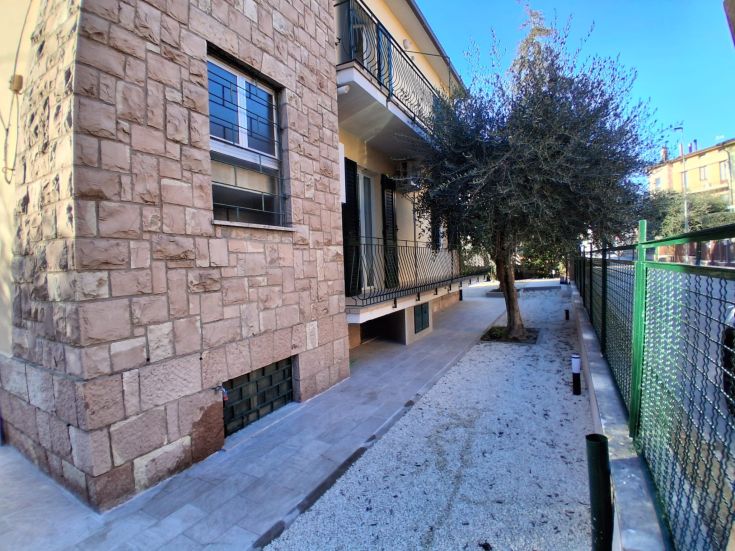 A modern building with a stone facade surrounded by a tree in a serene setting.