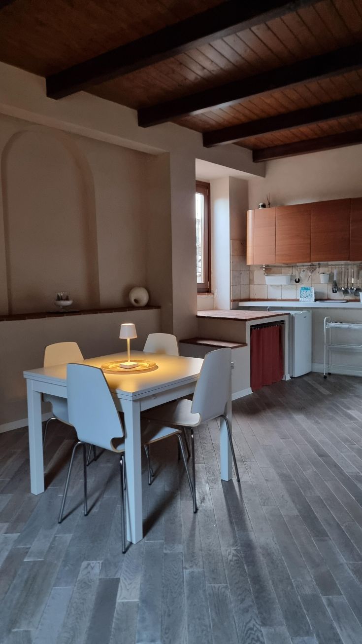 Bright living room with dining table and kitchenette, perfect for a stay in a historic setting.