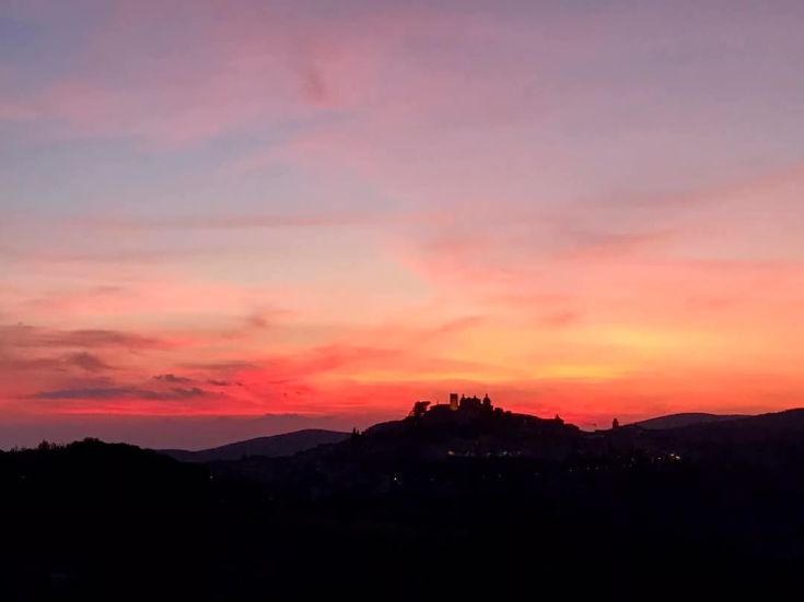 A sunset painting the hills and distant castle, creating a peaceful atmosphere.