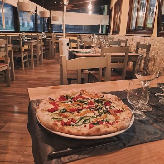 sala pizzeria con tavoplo apparecchiato e pizza servita 
