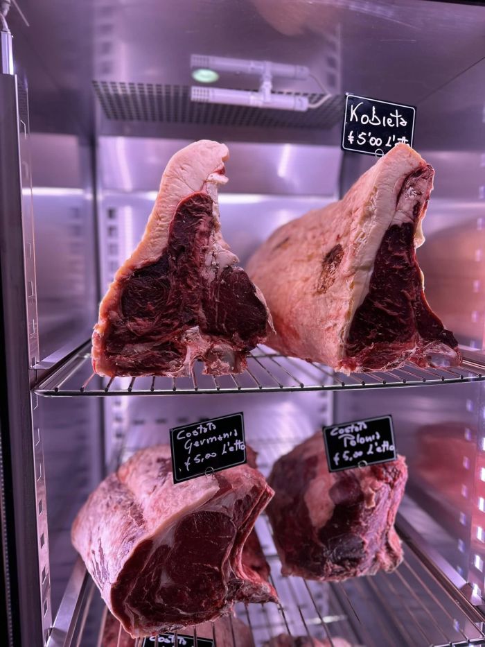 bistecche di vitello disposte su due piani di in un frigo illuminato 