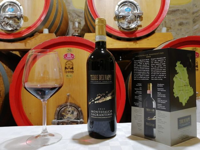 una bottiglia di vino sopra un tavolo con dietro delle botti 