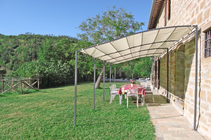 A farmhouse surrounded by vast green space equipped with umbrellas and tables, perfect for outdoor relaxation.