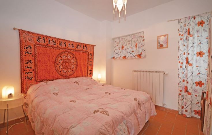 Simple room with floral details and an orange tapestry on the walls.