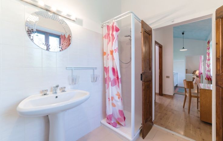 Bright contemporary bathroom featuring a shower, round mirror, and modern furnishings.
