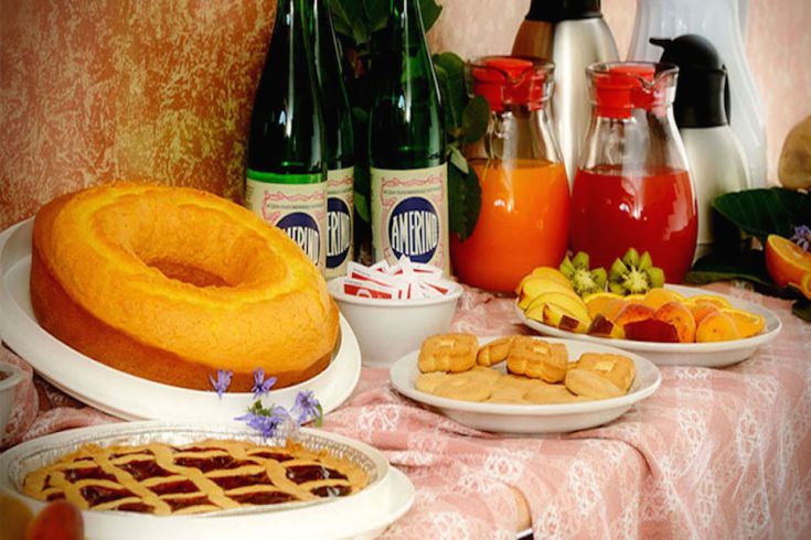 Un tavolo apparecchiato con dolci, frutta e bevande, ideale per una colazione semplice e accogliente.