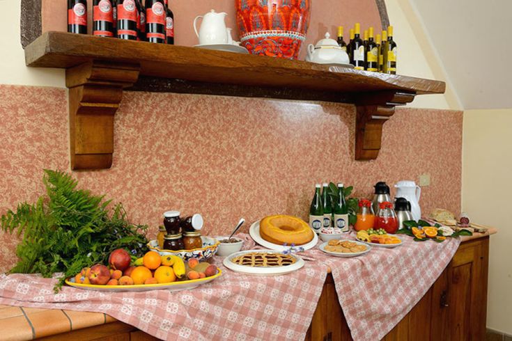 Un tavolo allestito con specialità tipiche e bevande in un agriturismo dal clima familiare.