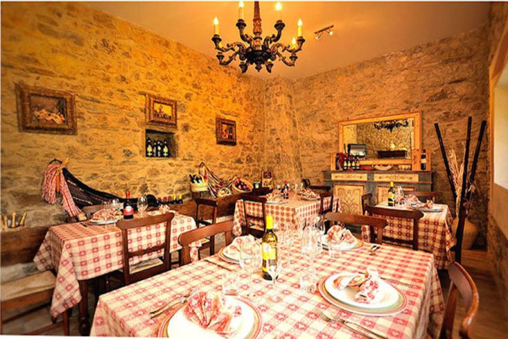 Ambiente semplice e ospitale di un ristorante tradizionale, con tavoli ben sistemati e pareti in pietra.