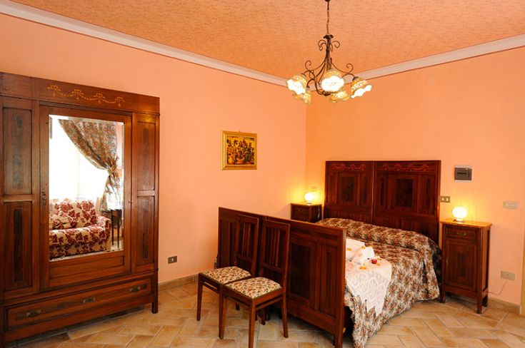 Camera tranquilla con arredi in legno, illuminazione soft e atmosfera accogliente.