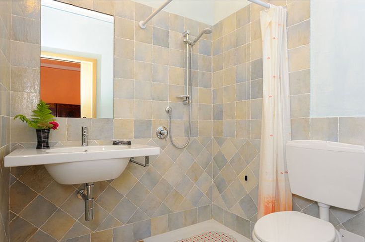 Bagno moderno arredato con piastrelle chiare, dotato di doccia e lavabo in un ambiente semplice e confortevole.