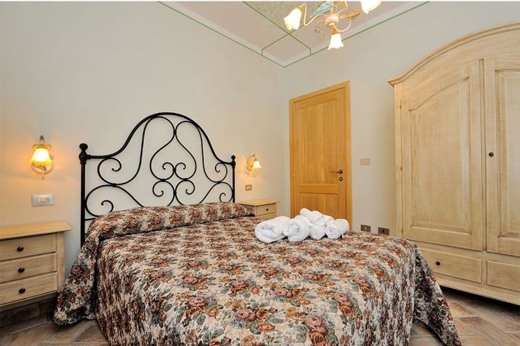 Spazio intimo con letto matrimoniale e mobili classici. Ambiente tranquillo e confortevole.