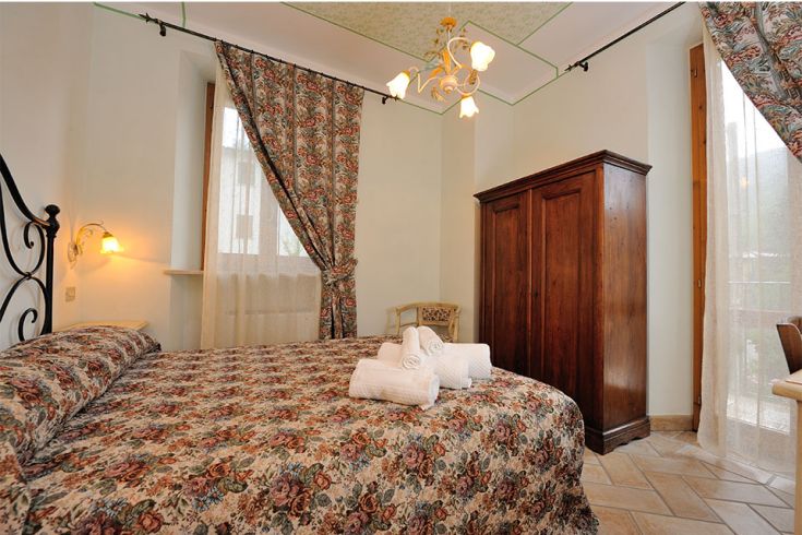 Spazio con decorazioni floreali, armadio in legno e luce naturale. Soggiorno confortevole in agriturismo.