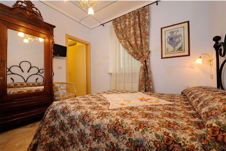 Camera semplice e confortevole con arredi in stile tradizionale, perfetta per un soggiorno immerso nella natura.