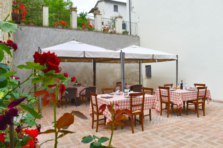 Un ristorante all'aperto, situato in un ambiente verde e decorato con piante e fiori. Ideale per gustare un pasto all'aria aperta.