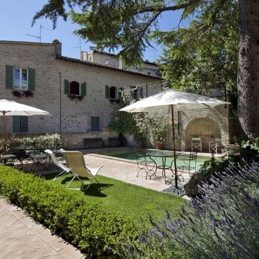 A well-maintained garden with a swimming pool, equipped with umbrellas and outdoor furniture for relaxation.