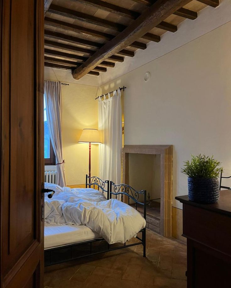 Simple room with iron bed and lamp, featuring warm lighting and rustic decor.