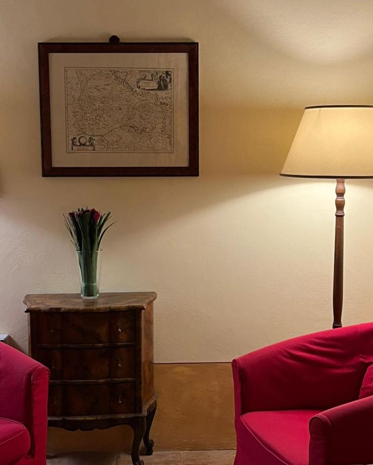 A cozy corner with a warm lamp, a wooden table, and a piece of art hanging on the wall.