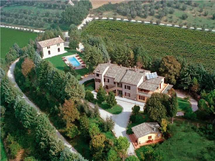 Un domaine paisible avec une villa et des cottages, entouré de zones vertes et de paysages vallonnés.