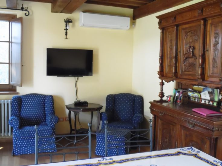 Salon simple avec télévision et fauteuils, idéal pour des moments de détente.