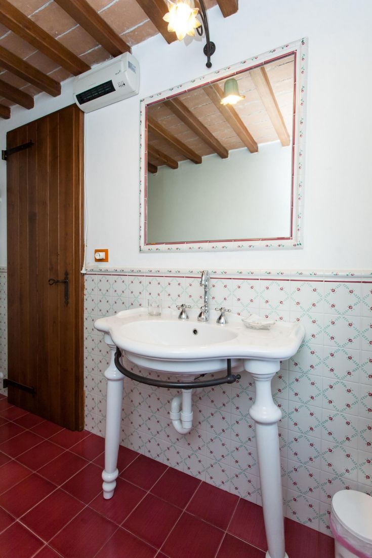 Une salle de bain simple avec un lavabo fonctionnel, quelques décorations et des poutres apparentes.