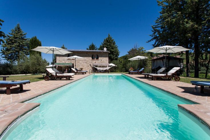 Une zone de détente avec une piscine entourée de verdure, située dans un domaine paisible.