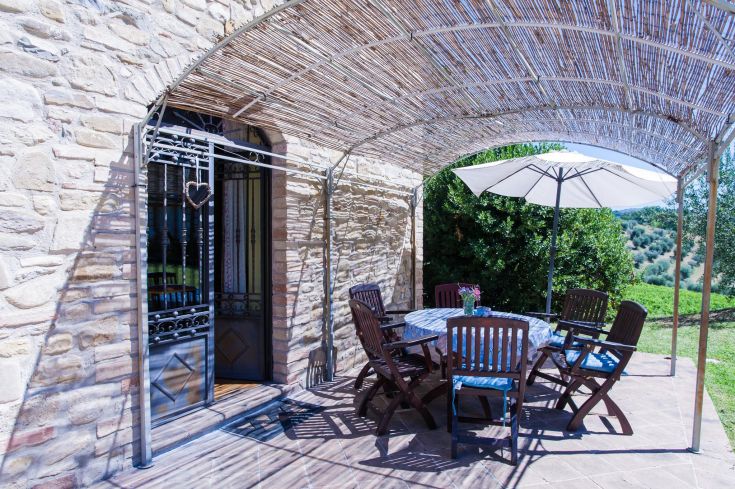 Un espace extérieur serein avec une table et des chaises en bois, entouré de la nature typique de la campagne ombrienne.