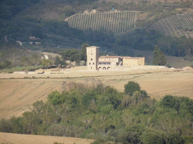 Scène d'un domaine historique entouré de verdure luxuriante, de collines et de vignobles.