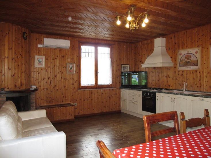 Un salon simple avec cuisine, meublé en bois et baigné de lumière naturelle.