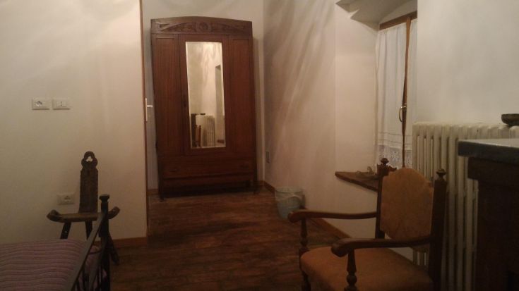 Un coin simple et confortable d'une chambre, avec un miroir et des meubles en bois clair.