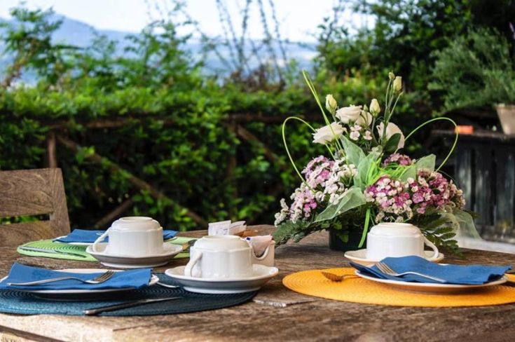 Table de petit-déjeuner en plein air décorée de fleurs et d'un ensemble de tasses à café.
