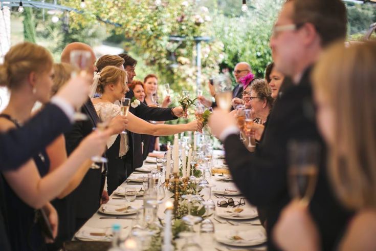 Un toast célébrant un mariage en extérieur avec des amis et la famille rassemblés pour fêter ensemble.