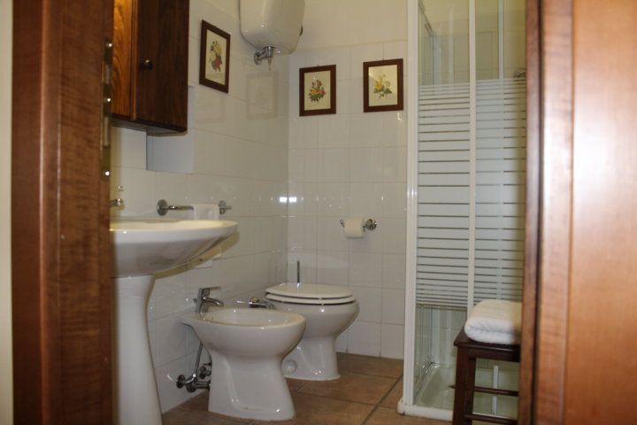 Salle de bain spacieuse et lumineuse avec douche, lavabo et toilettes, aménagée avec praticité.