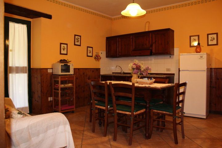 Cuisine simple d'un agriturismo en Ombrie, équipée d'une table et de chaises en bois et de décorations rustiques.