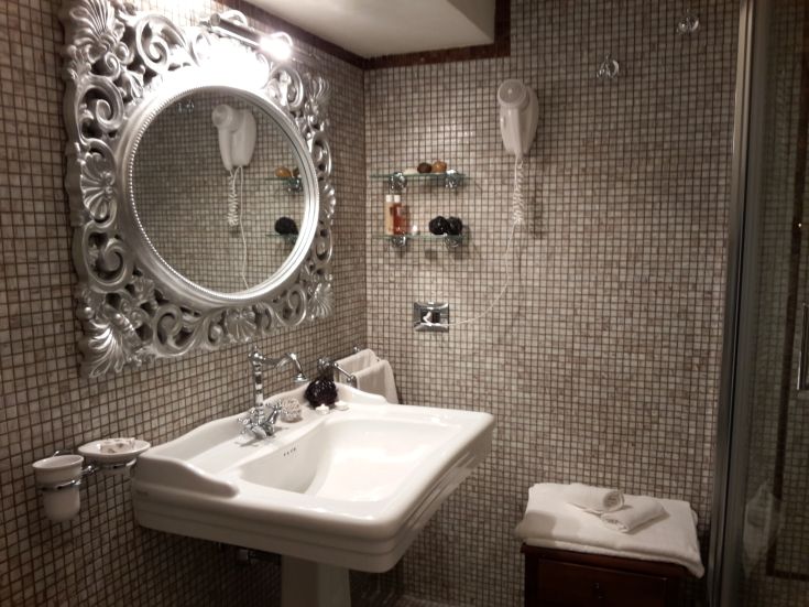 Elegantes Badezimmer mit Mosaikfliesen und einem dekorierten Spiegel, eine schlichte Entspannungsecke.