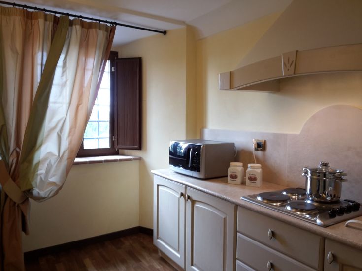 Geräumige und gut beleuchtete Küche mit einfachen Möbeln und einer funktionalen Kochnische für gesellige Momente.