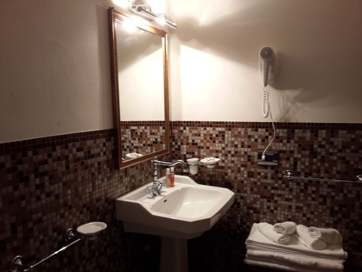 Ein minimalistisches Badezimmer mit Waschbecken, Spiegel und hellen Handtüchern, ideal für Entspannungsmomente.