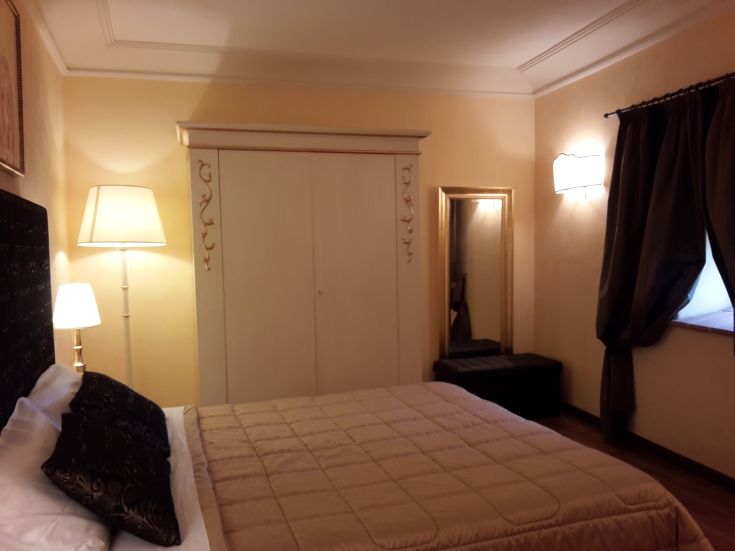 Gemütliches Zimmer mit einem Doppelbett, einem Kleiderschrank und sanfter Beleuchtung, perfekt für entspannende Momente.