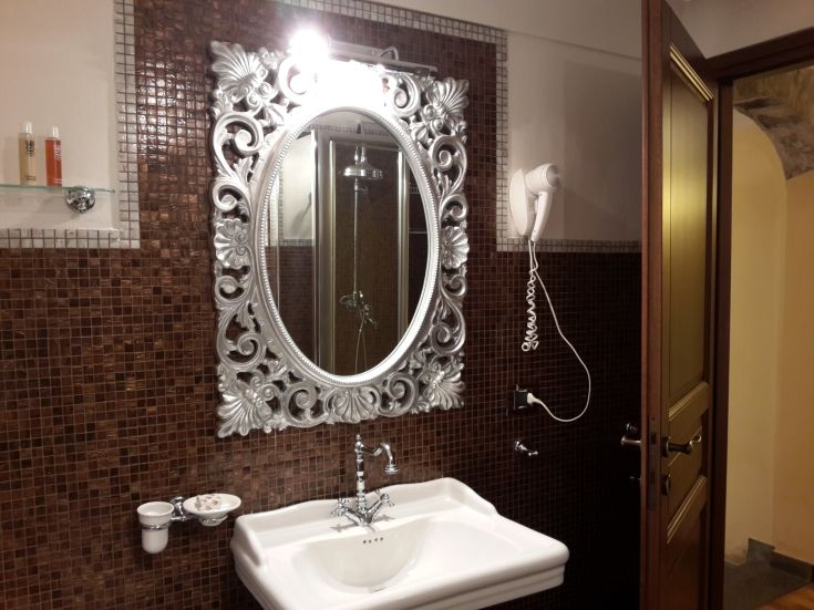 Ein einfaches Badezimmer mit einem dekorierten Spiegel und einem schlichten Waschbecken, ideal zum Entspannen.